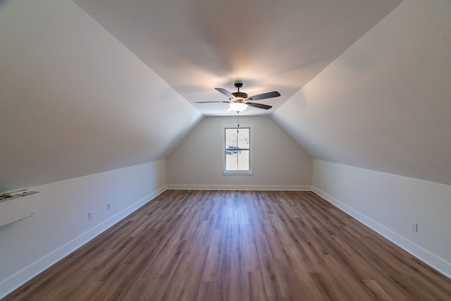 additional living space with dark wood-style floors, vaulted ceiling, baseboards, and a ceiling fan