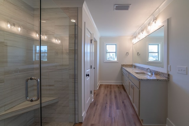 bathroom with a stall shower, baseboards, visible vents, ornamental molding, and vanity