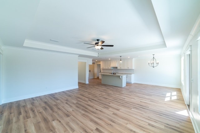 unfurnished living room featuring a raised ceiling, a sink, and baseboards