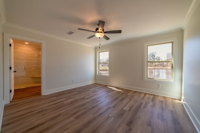 empty room with baseboards, dark wood finished floors, visible vents, and crown molding