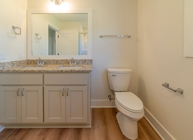 bathroom with wood finished floors, a sink, toilet, and baseboards