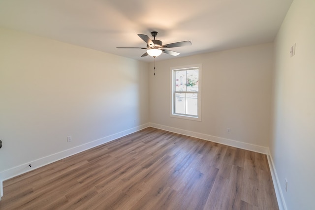 empty room with a ceiling fan, baseboards, and wood finished floors