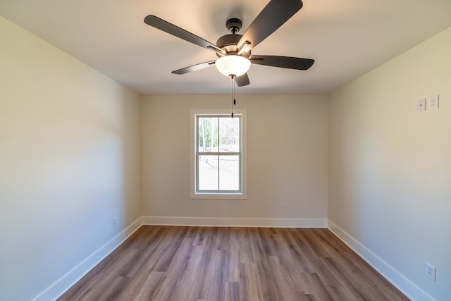 empty room featuring ceiling fan, baseboards, and wood finished floors