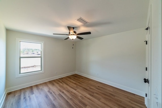 empty room with visible vents, ceiling fan, baseboards, and wood finished floors