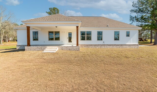 rear view of property featuring a yard, a shingled roof, and a patio