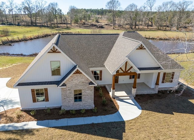 view of front of home featuring stone siding and roof with shingles