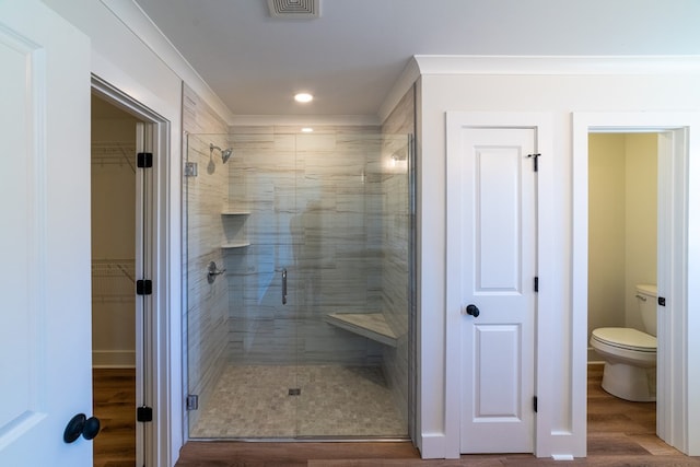 full bathroom with toilet, wood finished floors, visible vents, a stall shower, and crown molding