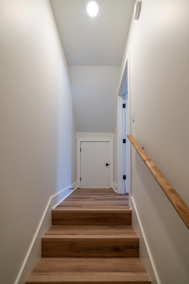 staircase with vaulted ceiling, baseboards, and wood finished floors