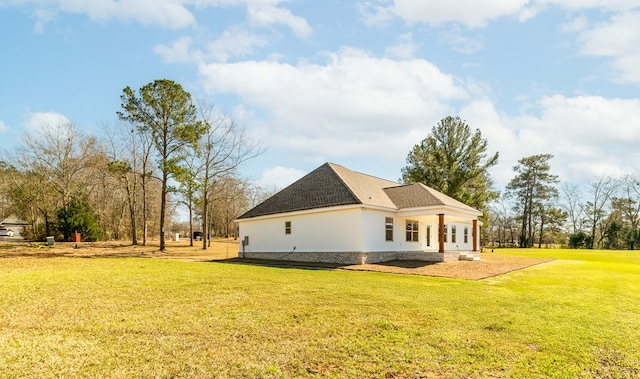 view of side of property with a shingled roof and a yard