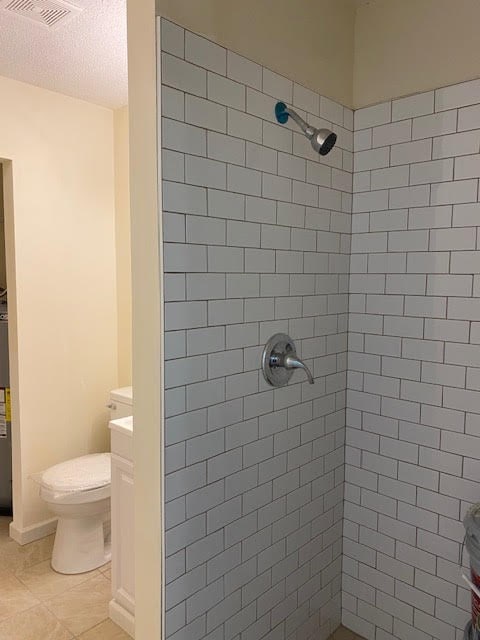 2308 Debbie Dr, Dothan, AL 36301 - bathroom featuring tiled shower, vanity, tile patterned floors, and gas water heater