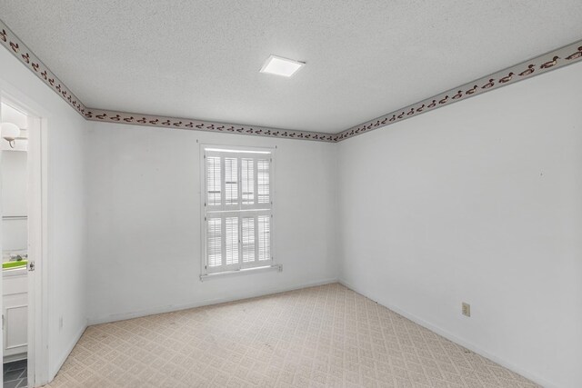 spare room featuring baseboards, carpet flooring, and a textured ceiling
