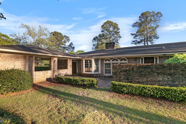 exterior space with brick siding, a chimney, and a front lawn