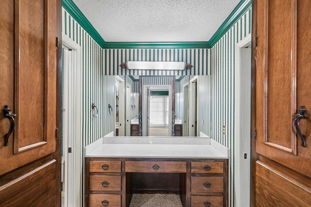 bathroom featuring a textured ceiling, vanity, and wallpapered walls