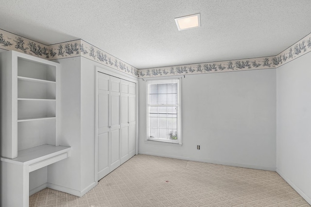 unfurnished bedroom featuring a closet, carpet flooring, a textured ceiling, and baseboards