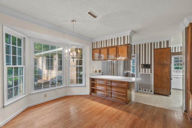 kitchen featuring visible vents, a notable chandelier, ornamental molding, light wood-type flooring, and brown cabinets