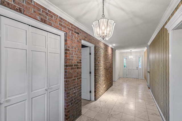 corridor featuring brick wall, a notable chandelier, marble finish floor, and ornamental molding