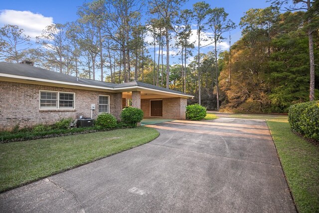 ranch-style house featuring concrete driveway, an attached carport, a front lawn, and brick siding