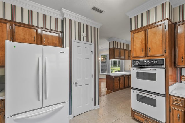 kitchen with ornamental molding, light countertops, white appliances, brown cabinets, and light tile patterned flooring
