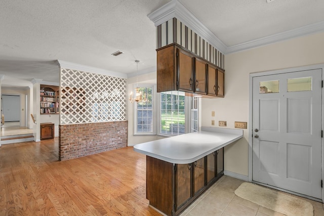 kitchen with a peninsula, visible vents, a textured ceiling, and crown molding
