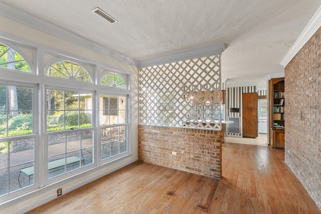 kitchen with visible vents, brick wall, and a textured ceiling