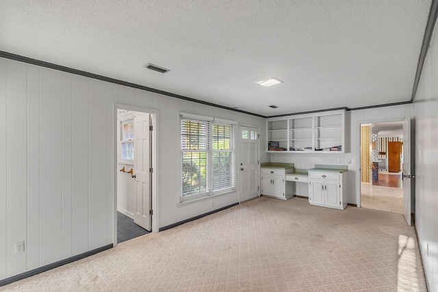 interior space featuring light carpet, visible vents, a textured ceiling, and crown molding