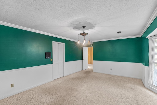 spare room featuring a textured ceiling, ornamental molding, visible vents, and carpet floors
