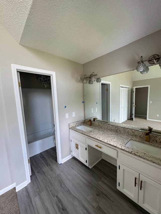107 Comanche Cir, Enterprise, AL 36330 - bathroom featuring double vanity, a textured ceiling, wood finished floors, and a bath