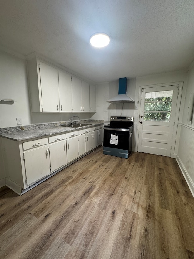1208 Jonathan St, Dothan, AL 36301 - kitchen with range with electric stovetop, wall chimney range hood, light wood finished floors, white cabinetry, and light countertops