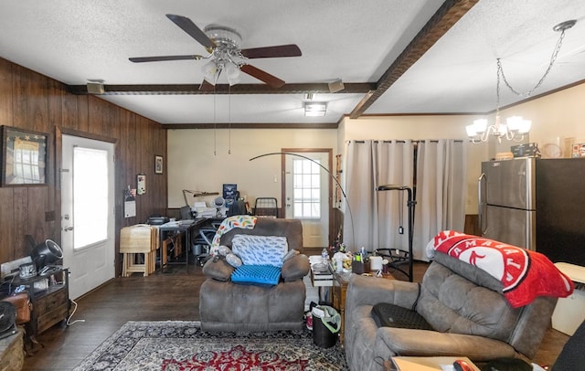 living room with beam ceiling, dark hardwood / wood-style floors, wood walls, a textured ceiling, and ceiling fan with notable chandelier