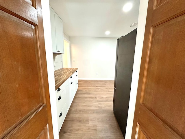 kitchen with light wood-type flooring, white cabinetry, and butcher block counters