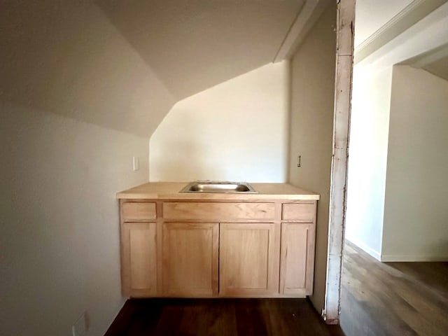 bar featuring light brown cabinets, dark hardwood / wood-style flooring, lofted ceiling, and sink