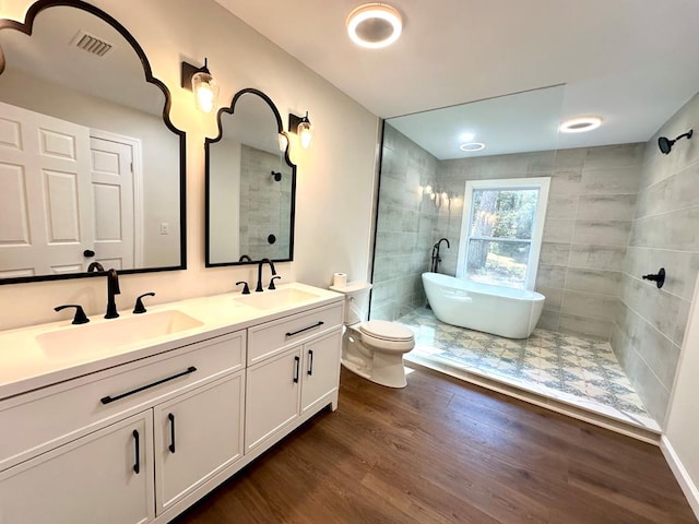 full bathroom with plus walk in shower, hardwood / wood-style floors, vanity, and toilet