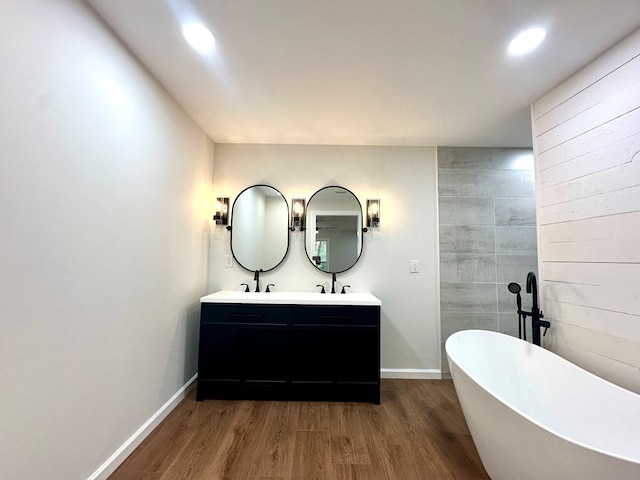 bathroom with a bathing tub, vanity, and wood-type flooring