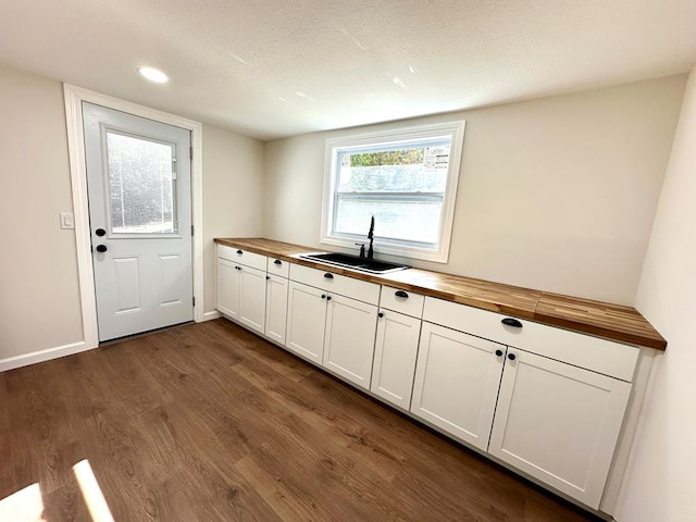 kitchen with dark hardwood / wood-style flooring, white cabinetry, butcher block counters, and sink