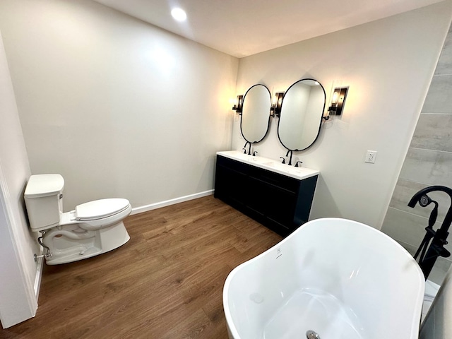 bathroom featuring a bath, vanity, hardwood / wood-style flooring, and toilet