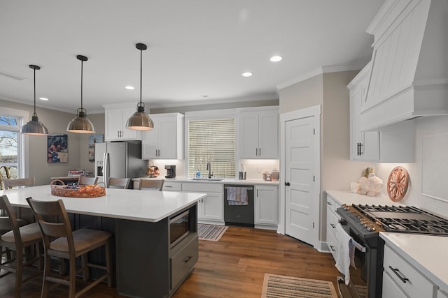 kitchen featuring sink, custom exhaust hood, appliances with stainless steel finishes, pendant lighting, and white cabinets