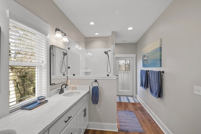 bathroom featuring hardwood / wood-style floors, vanity, and a tile shower