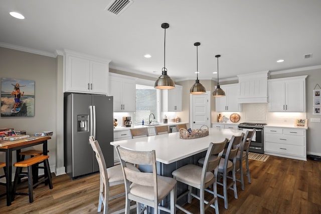 kitchen featuring white cabinetry, appliances with stainless steel finishes, decorative light fixtures, and a kitchen island