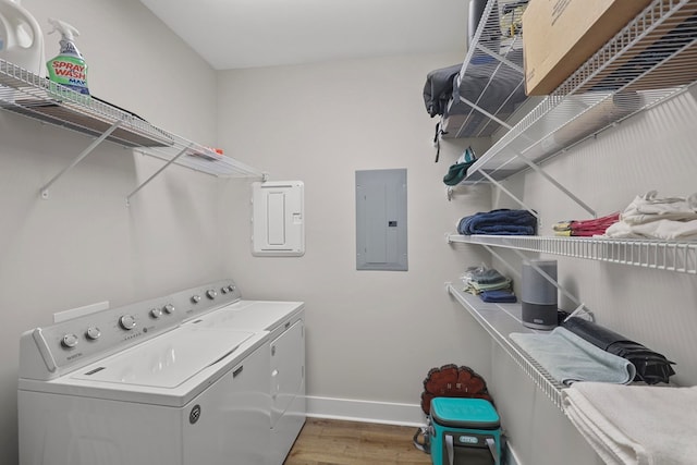 laundry area with electric panel, independent washer and dryer, and light hardwood / wood-style floors