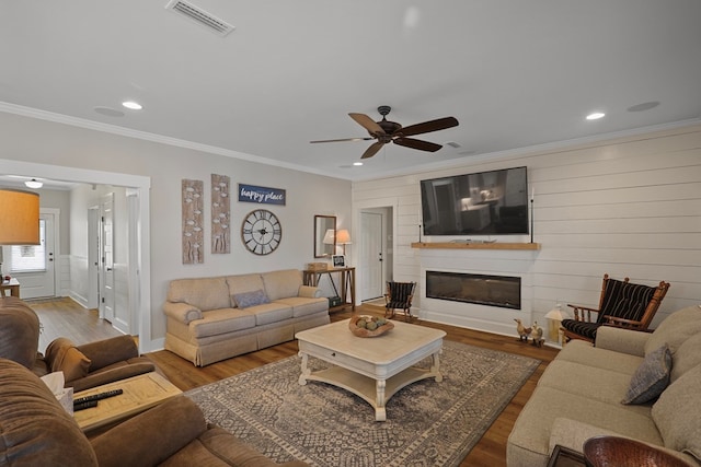 living room featuring hardwood / wood-style flooring, ceiling fan, and ornamental molding