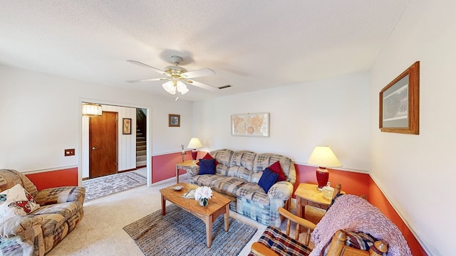 carpeted living room with ceiling fan and a textured ceiling