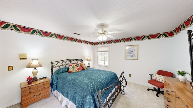 bedroom with a textured ceiling, light colored carpet, and ceiling fan