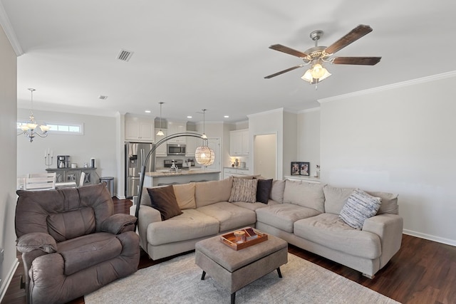 living room with dark wood-type flooring, ceiling fan with notable chandelier, and ornamental molding