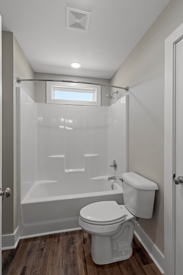 bathroom with hardwood / wood-style floors, toilet, and washtub / shower combination