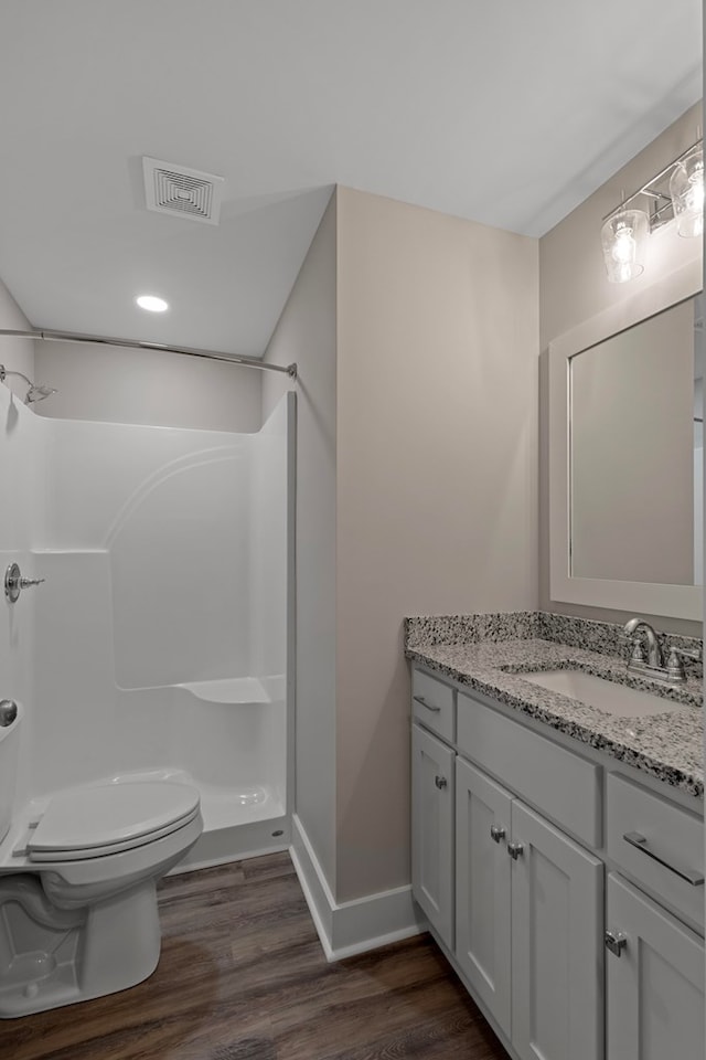 bathroom with wood-type flooring, vanity, toilet, and walk in shower