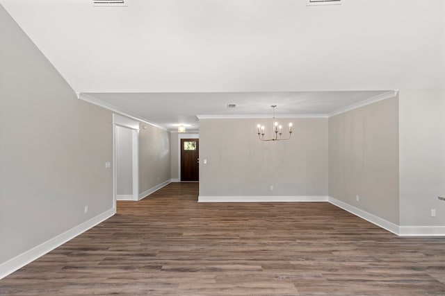 spare room with crown molding, dark wood-type flooring, and a notable chandelier