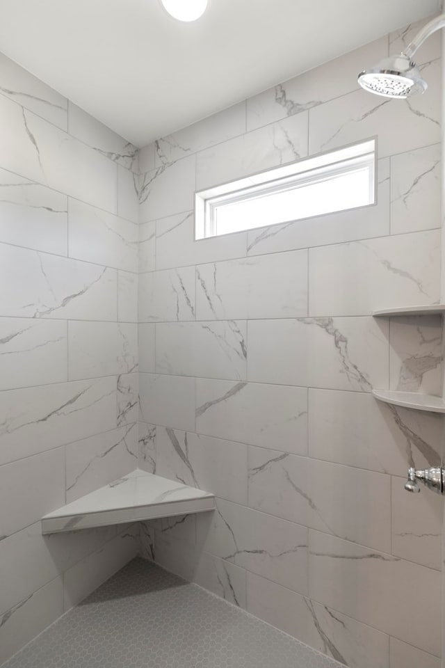 bathroom featuring a tile shower and a healthy amount of sunlight