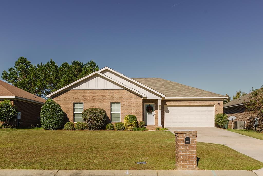 ranch-style house featuring a garage, driveway, brick siding, and a front yard