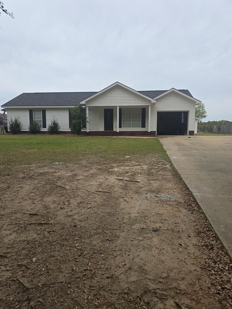 ranch-style home with a front lawn, an attached garage, and concrete driveway