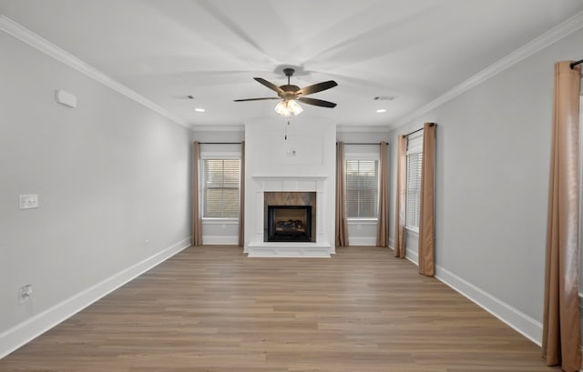 unfurnished living room featuring a high end fireplace, ornamental molding, ceiling fan, and light wood-type flooring